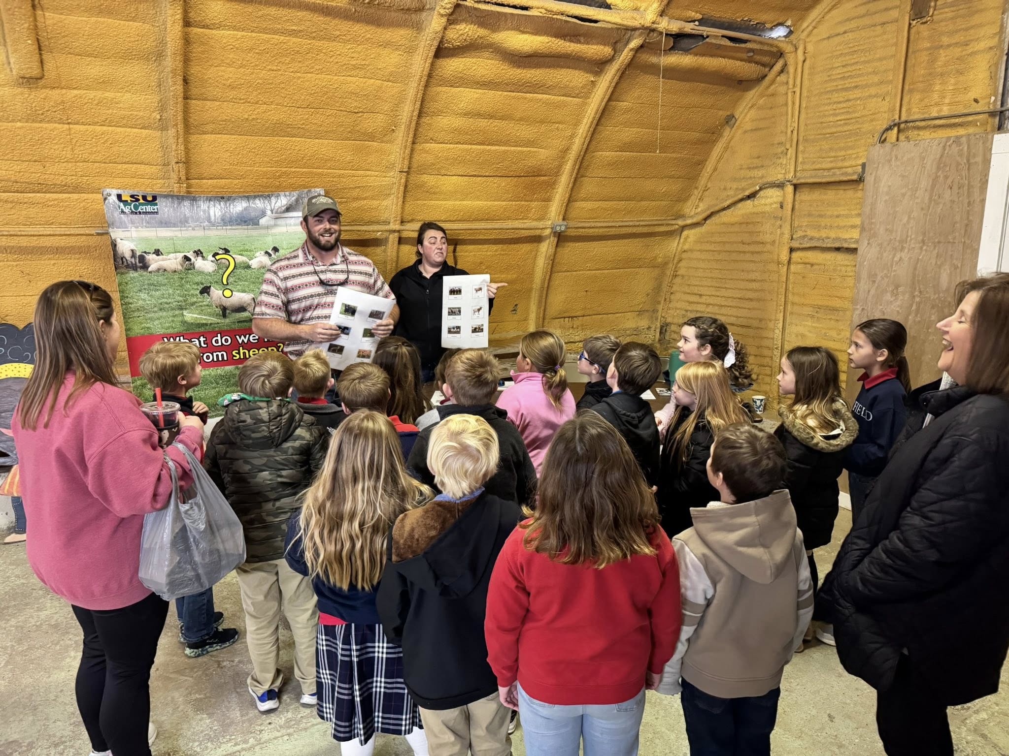A man and a woman talking to a group of kids and adults.
